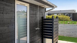 Un bâtiment moderne avec une façade en bois sombre, une porte en verre et un portail en métal.