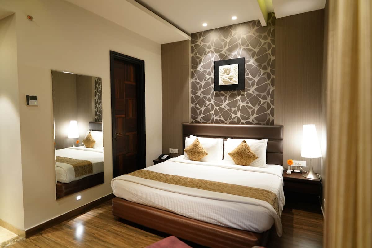 Ein Hotelzimmer mit einem großen Bett, einem Spiegel, einem Wandbild und einem Nachttisch mit Lampe.
