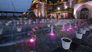 A hotel with a fountain area, potted plants, and a restaurant entrance. - The Vivaan Hotel & Resorts (Nilokheri)