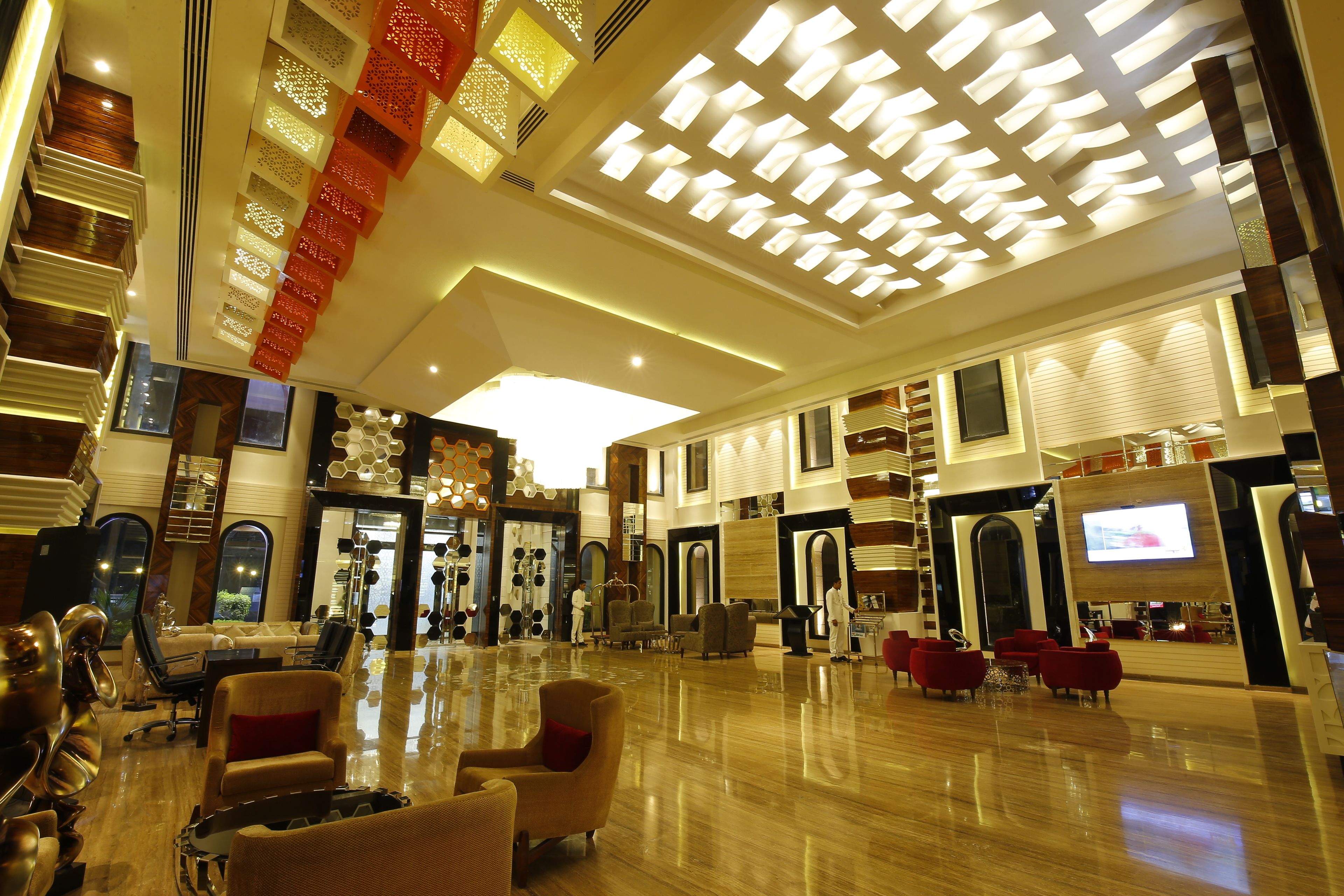 A spacious lobby with a high ceiling, multiple seating areas, and a large TV screen.
