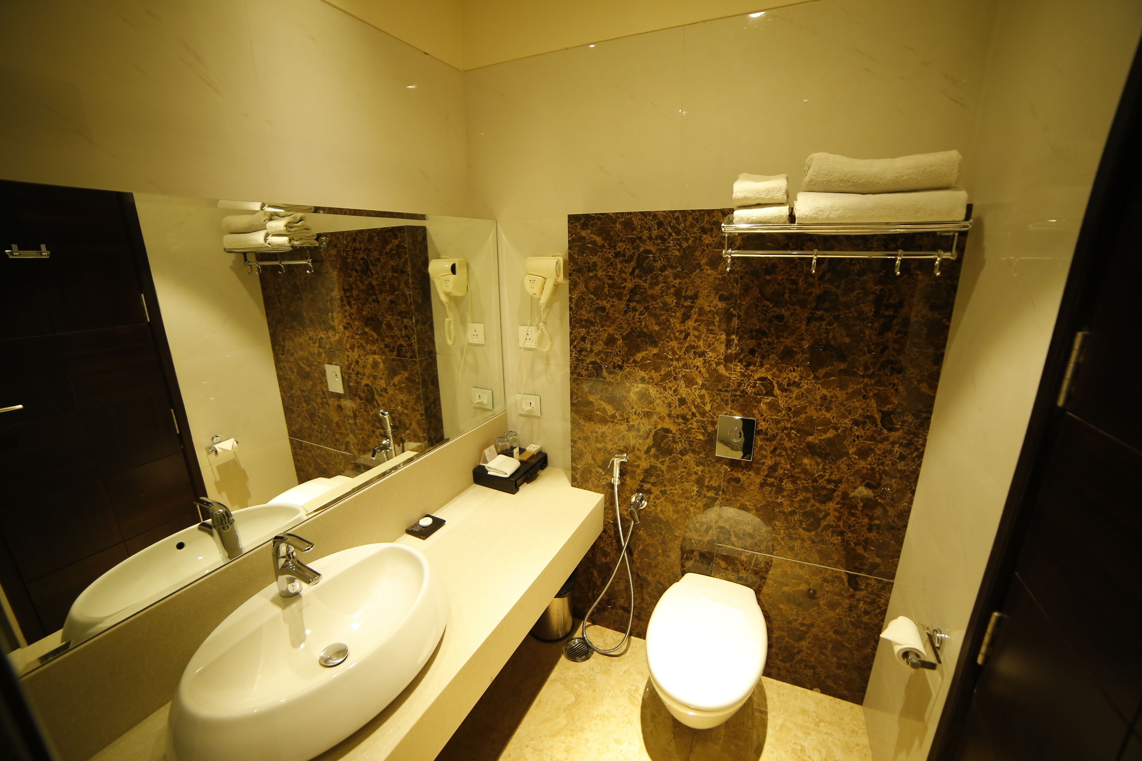 A modern bathroom with a sink, mirror, towel rack, and a toilet.