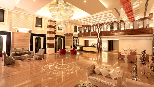 A spacious lobby with a high ceiling, a large chandelier, and a reception desk. - The Vivaan Hotel & Resorts (Nilokheri)