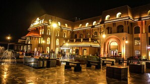 A spacious courtyard with a fountain, outdoor seating, and a building with multiple arches and a balcony. - The Vivaan Hotel & Resorts (Nilokheri)