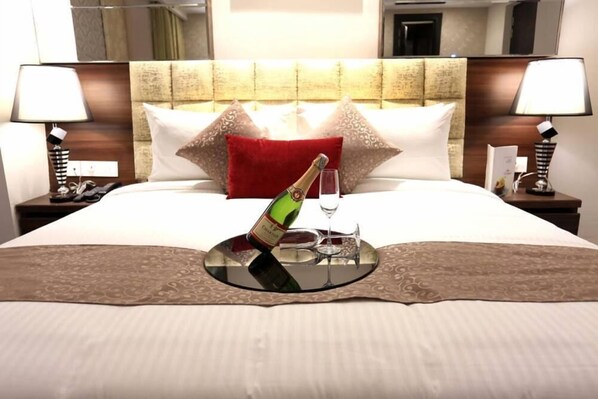 A hotel room with a neatly made bed, a bedside table with a lamp, and a nightstand with a phone.