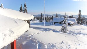 A snow-covered landscape with a wooden cabin and a red post in the foreground. - 3 bedroom stunning home in Sjusjøen (Sjusjøen)
