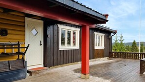 A wooden cabin with a red porch, a white door, and a window with a curtain. - 3 bedroom stunning home in Sjusjøen (Sjusjøen)