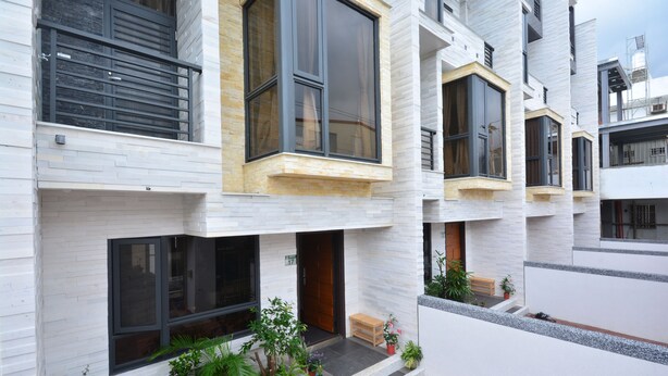 A multi-story residential building with large windows, a small outdoor seating area, and potted plants. - Hellostay B&B Hualien Jian (Ji'an)
