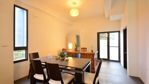 A dining area with a rectangular table, four chairs, a chandelier, a window, and a view of the outdoors. - Hellostay B&B Hualien Jian (Ji'an)