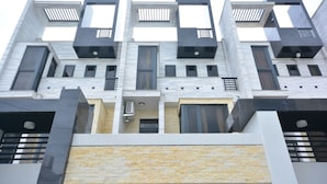 A modern multi-story building with a symmetrical facade, featuring a mix of rectangular and square windows, and a central air conditioning unit. - Hellostay B&B Hualien Jian (Ji'an)