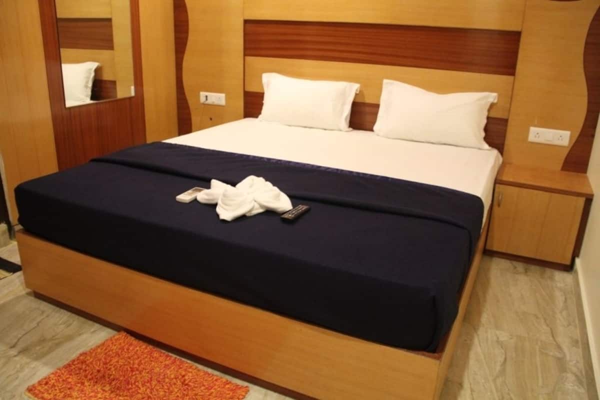 A hotel room with a wooden bed frame, white bedding, and a small bedside table.