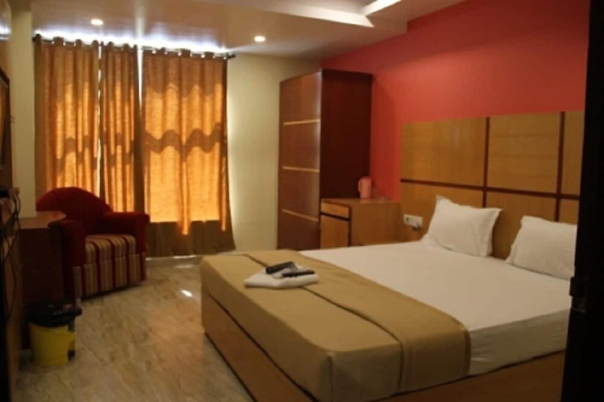 A hotel room with a large bed, a desk, a chair, and a wardrobe.