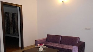 Un salón con una mesa de centro de madera oscura, un sofá morado y una mesita con un jarrón de flores.