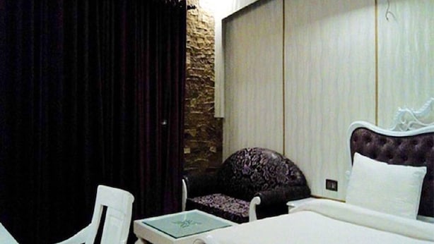 Una habitación de hotel con una cama, una silla, una mesita y una pared de piedra.