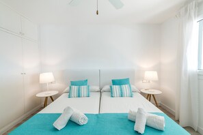 Ein Doppelzimmer mit zwei Betten, jeweils mit Kissen und einem Nachttisch mit Lampe.