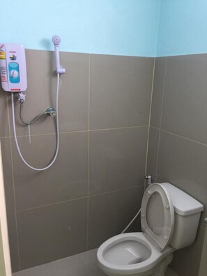 A small bathroom with a toilet, a shower unit, and a wall-mounted soap dispenser. - River Residence 2 (Saraburi)