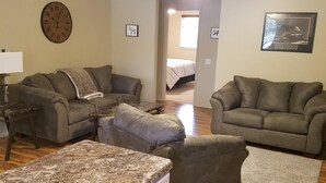 Ein Wohnzimmer mit zwei Sofas, einem Couchtisch, einer Uhr und einem Deckenventilator.