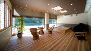 A room with wooden flooring, large windows, and a view of greenery outside. - Ryokan Ohashi (Misasa)