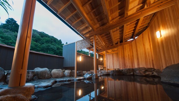 A wooden interior with a stone-lined pool reflecting the ceiling. - Ryokan Ohashi (Misasa)