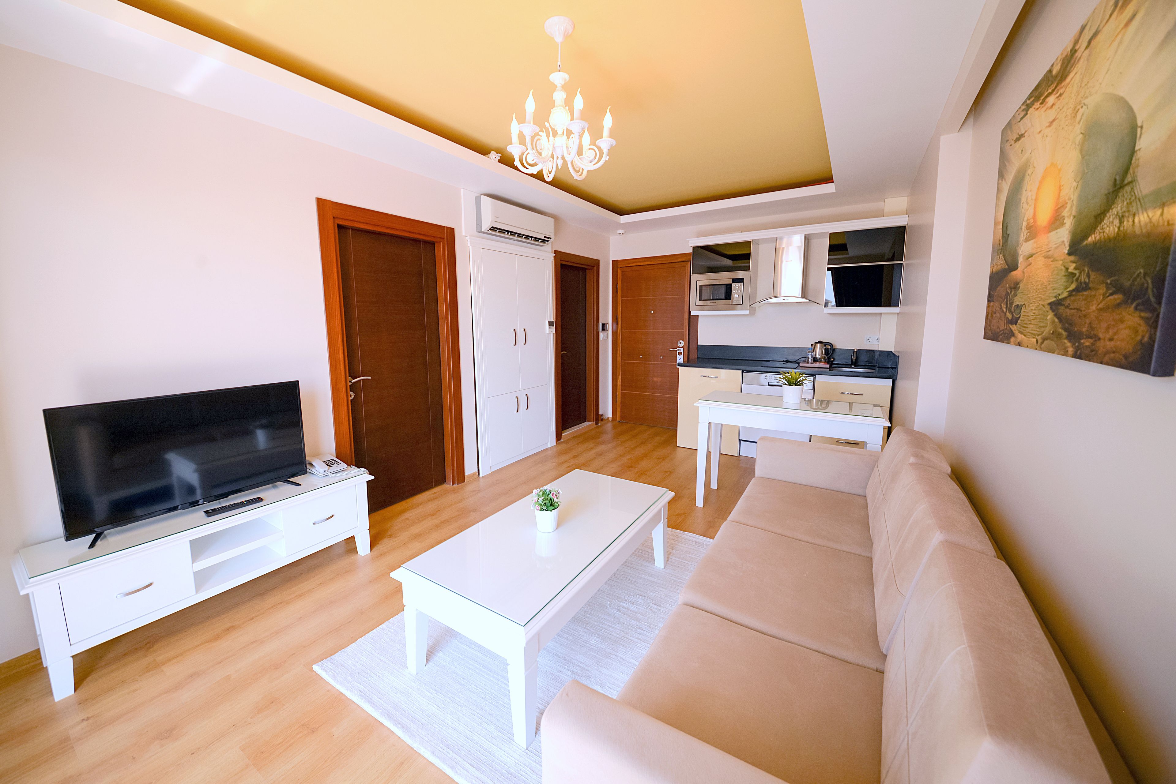 A living room with a TV, sofa, coffee table, and a painting on the wall.