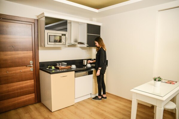 A compact kitchen with a microwave, a sink, and a small countertop. - Sarajevo Suit Hotel (Cayirova)
