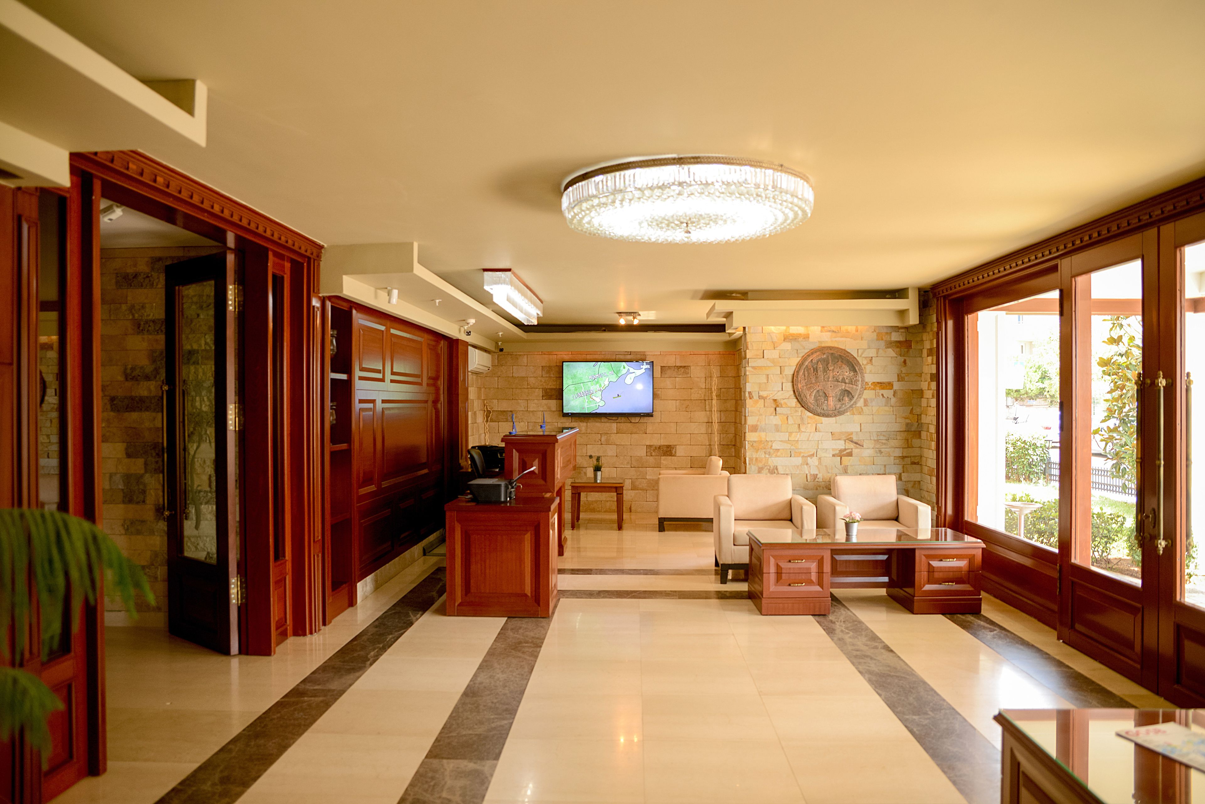 A spacious living area with a television, wooden furniture, and a chandelier.
