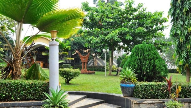 A garden with a stone staircase, potted plants, and a traditional decorative structure. - Evelyn Apartments (Kampala)