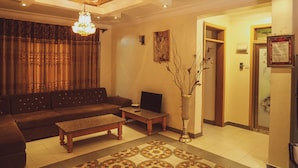 A living room with a sofa, coffee table, and a decorative vase. - Evelyn Apartments (Kampala)