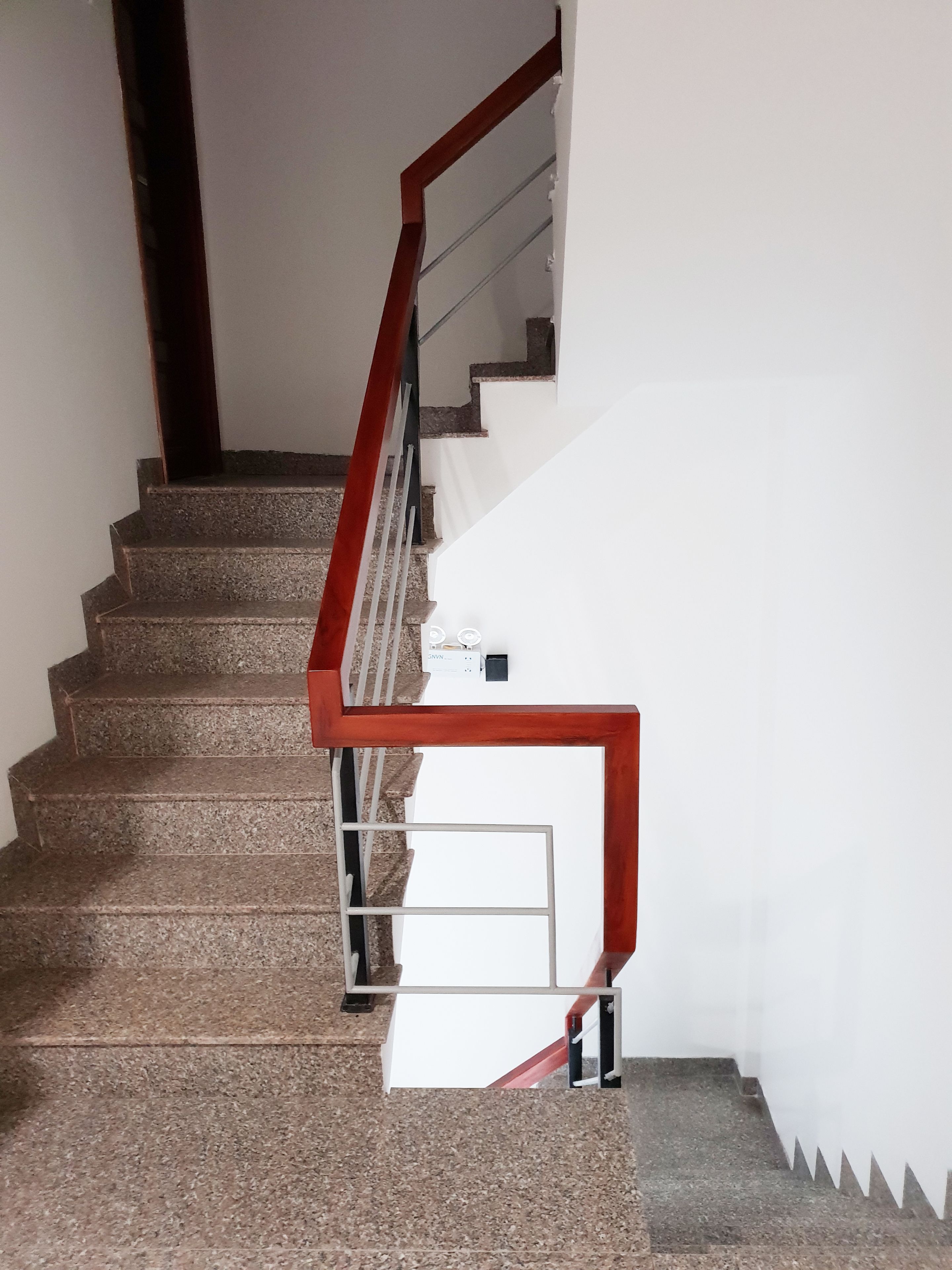 A staircase with granite steps and a wooden handrail.