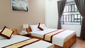 A hotel room with two beds, a nightstand with a lamp, a painting on the wall, and a window with curtains. - Khách sạn Quy Nhơn Center (Quy Nhon)