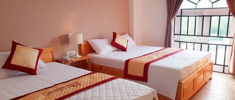 Two double beds with wooden headboards, a bedside table with a lamp, and a painting on the wall.
