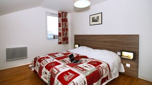 A bedroom with a bed, a window with curtains, a wall-mounted picture, and a ceiling light. - Cozy Chalet for You & Tails (Auris)