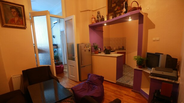 A compact living space with a dining area, a kitchenette, and a small entertainment setup. - Lilus Hostel (Batumi)