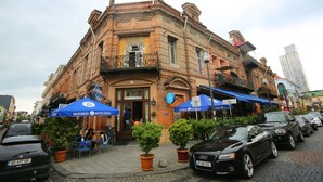 A historic building with outdoor seating and a cobblestone street. - Lilus Hostel (Batumi)