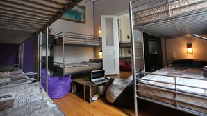A dorm-style room with bunk beds, a desk with a laptop, and a bean bag chair. - Lilus Hostel (Batumi)