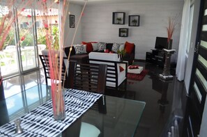 Una sala de estar moderna con una mesa de centro de vidrio, un sofá con cojines estampados y un televisor.