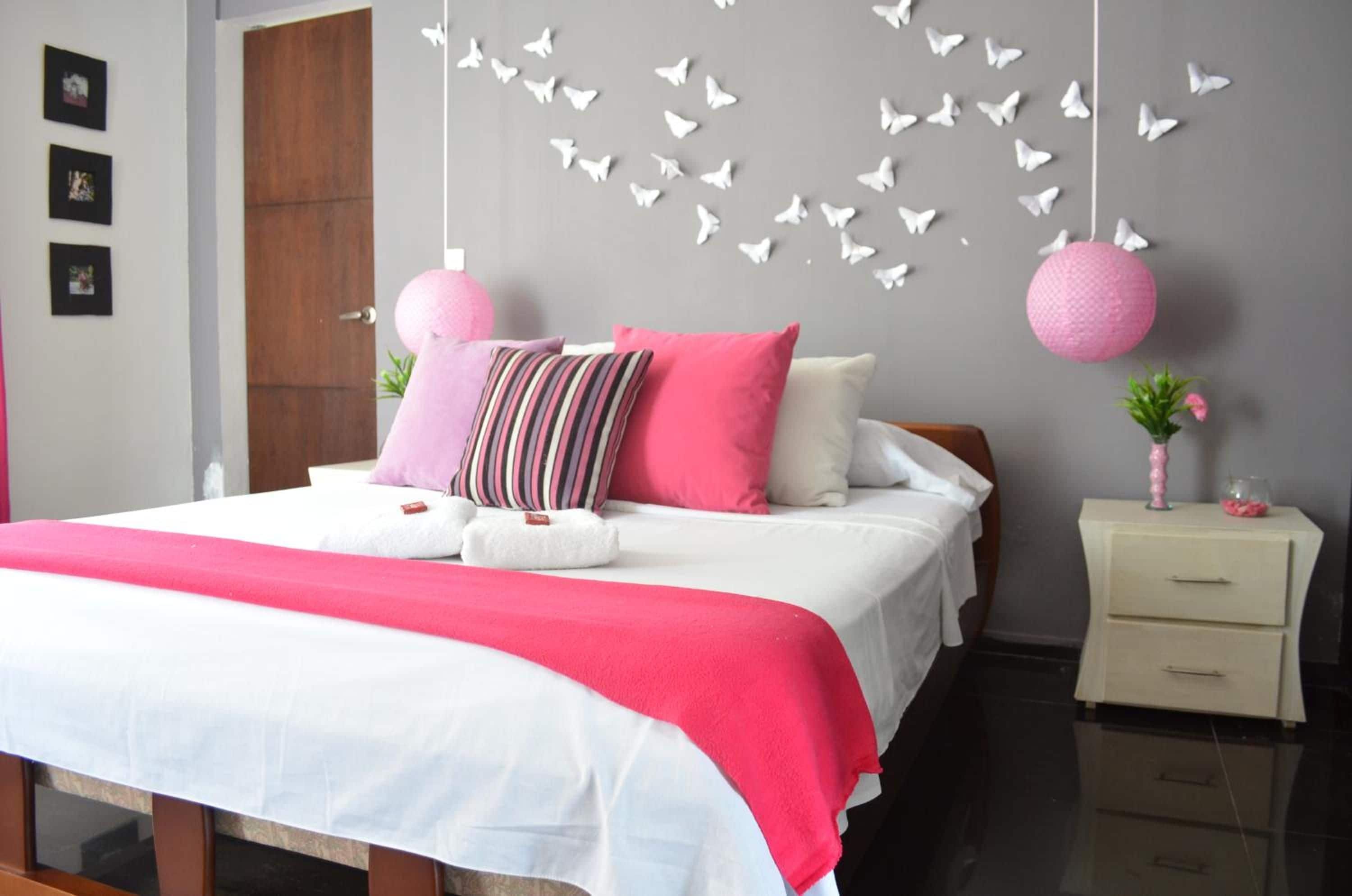 A bedroom with a bed, pillows, a nightstand, and decorative butterflies on the wall.