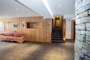 A wooden interior with a bed, a staircase, and a stone wall.