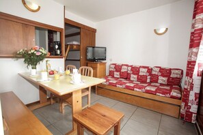 Ein gemütlicher, kompakter Wohnbereich mit Küchenzeile, Esstisch, Sofa und Fernseher.