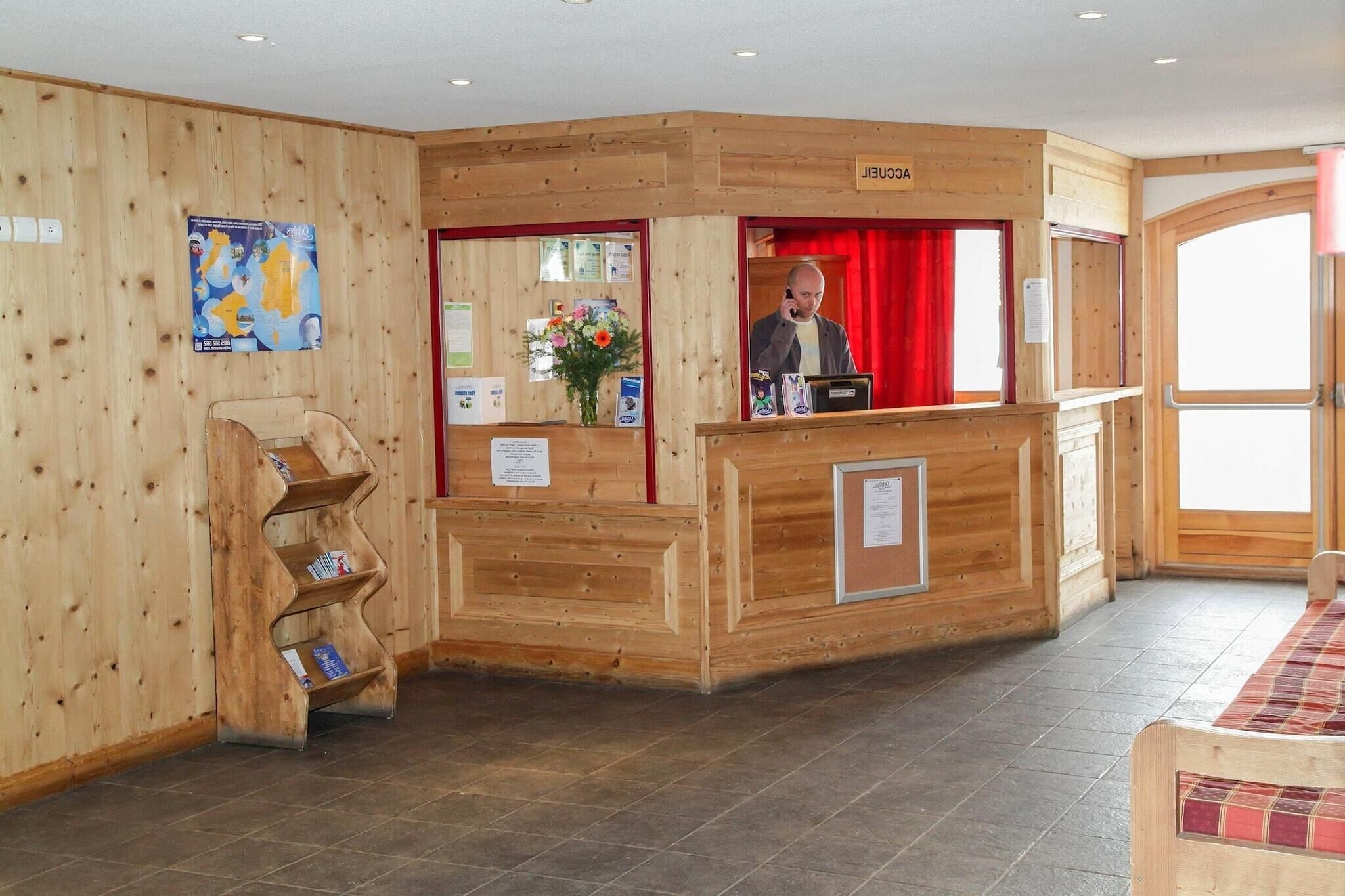 A reception area with a wooden desk, a red curtain, and a wooden wall with a map.