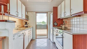 A kitchen with white cabinets, a built-in oven, and a window leading to a balcony. - Gorgeous home in Hejls with sauna (Hejls)