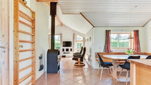 A modern kitchen with a large stove, wooden cabinets, and a dining area with a table and chairs. - Gorgeous home in Hejls with sauna (Hejls)