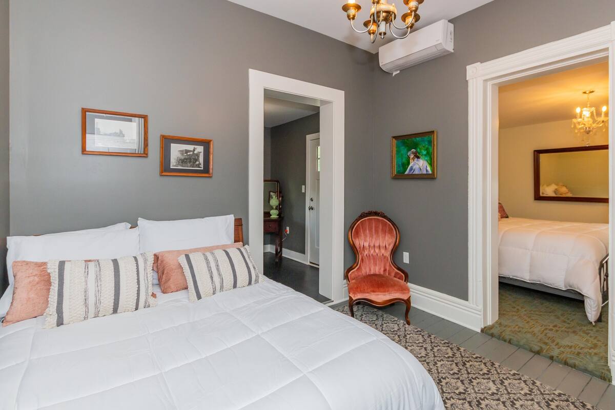 Ein Schlafzimmer mit einem großen Bett, einem Sessel und einer Tür zu einem anderen Raum.
