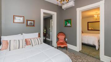 Ein Schlafzimmer mit einem großen Bett, einem Sessel und einer Tür zu einem anderen Raum.