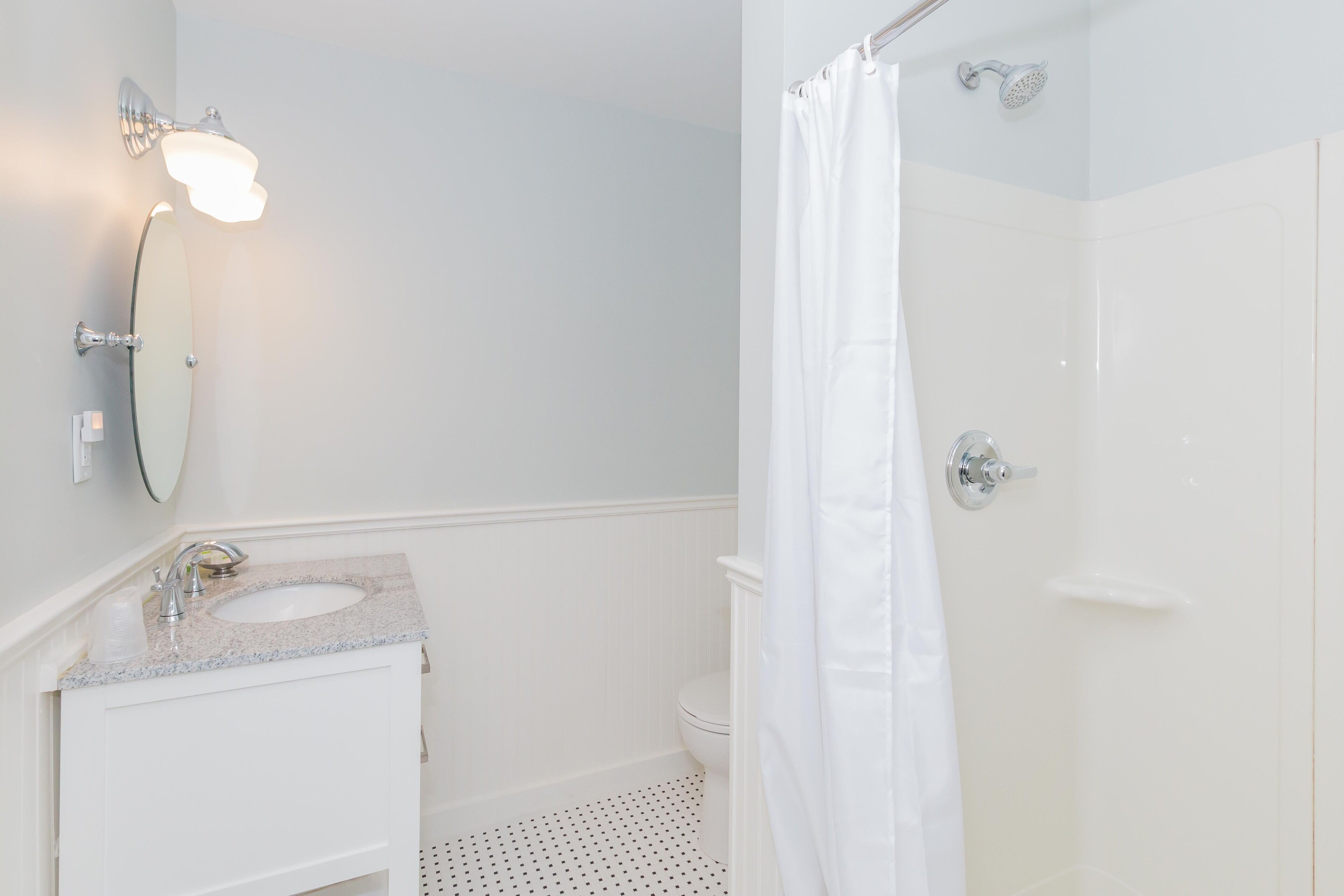 A bathroom with a sink, mirror, and shower.