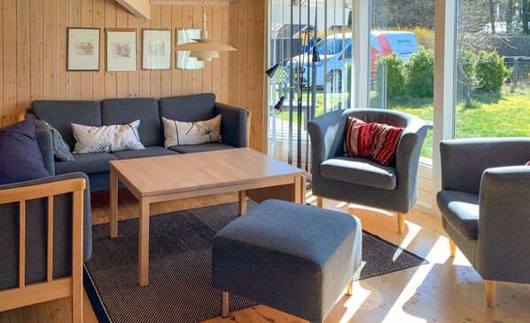 A modern living room with a sofa set, a coffee table, and a chair. There are framed pictures on the wall, and a car is visible through the window.