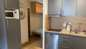 Eine kompakte Küche mit Mikrowelle, Geschirrspüler und Kaffeemaschine. Ein kleiner Essbereich mit Tisch und Stühlen ist vorhanden.