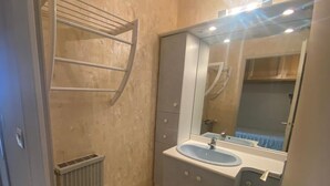 Ein kleines Badezimmer mit einem weißen Heizkörper, einem Waschbecken und einem Spiegel.