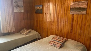 Ein Zimmer mit zwei Betten, Holzvertäfelung an den Wänden und Kunstwerken.