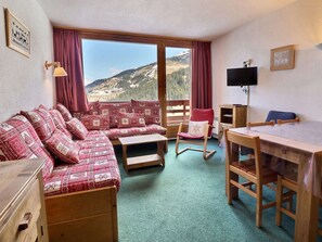 Ein gemütliches Zimmer mit einer Couch, einem Schaukelstuhl, einem Tisch und einem Fernseher.