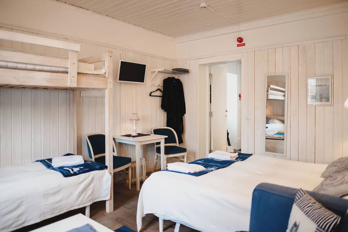 A room with bunk beds, a desk, chairs, a TV, and a mirror.